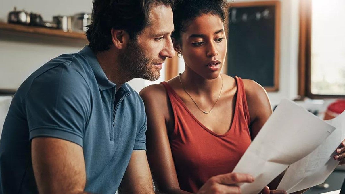 Photo of a couple reviewing paper and digital financial documents.