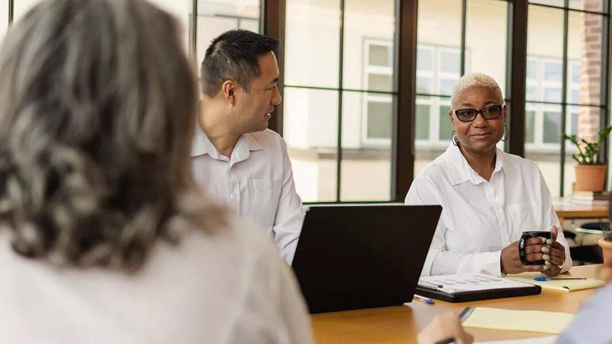Photo of a group of leaders sitting around a conference table discussing employee benefits.