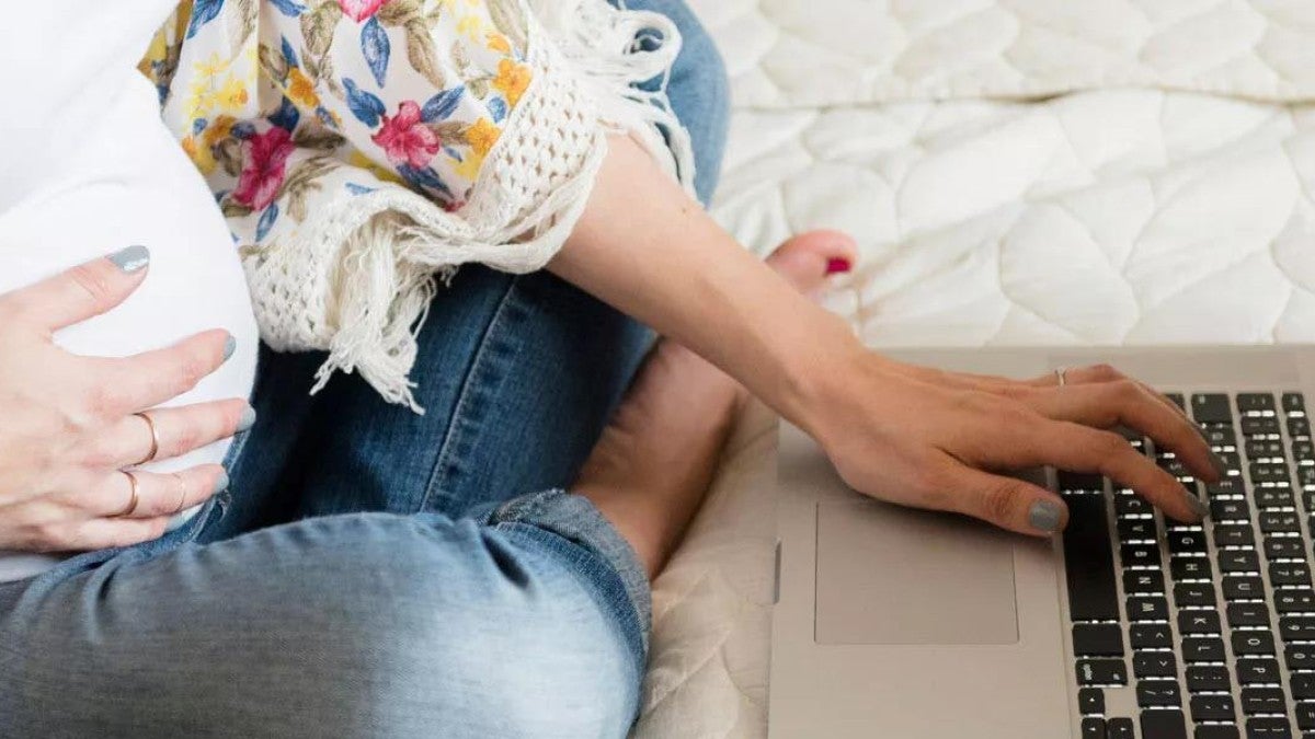 Pregnant woman surfing the web on a laptop