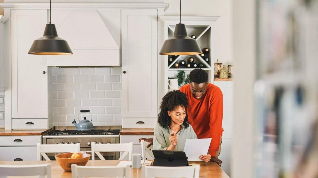 Young couple in their kitchen looking over documents as part of their financial planning.
