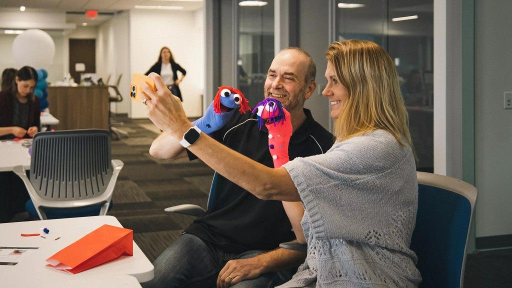 Principal employees volunteer at a mental health support event to make puppets for  children