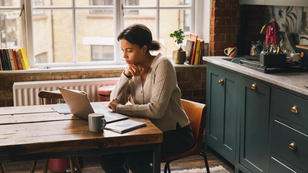 Photo of a woman working on a laptop in her home