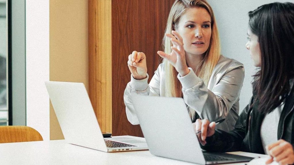 Dos mujeres revisando información sobre préstamos estudiantiles en computadoras.