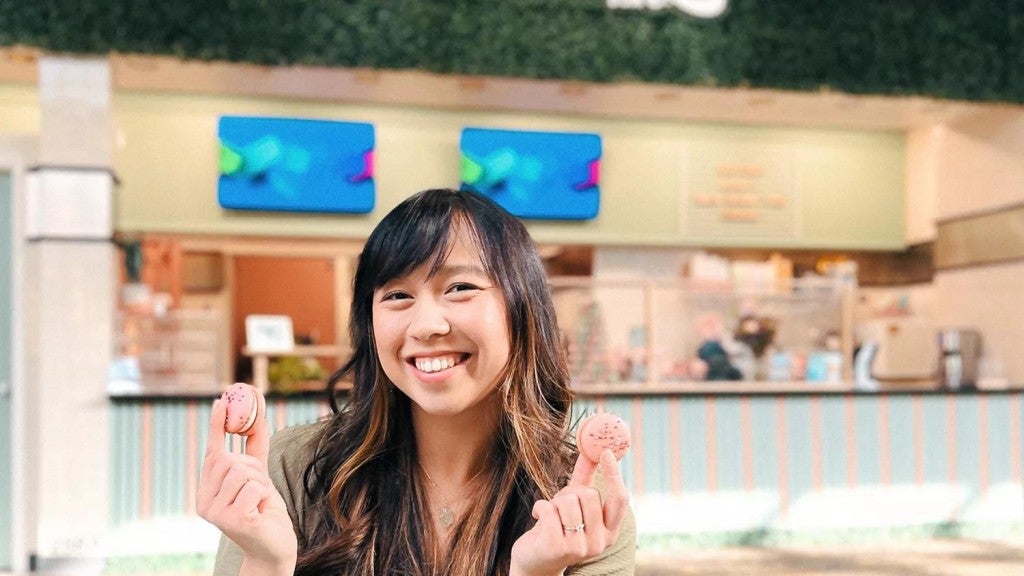 Anna Lam poses with colorful macarons in front of her bakery Good Day DSM.