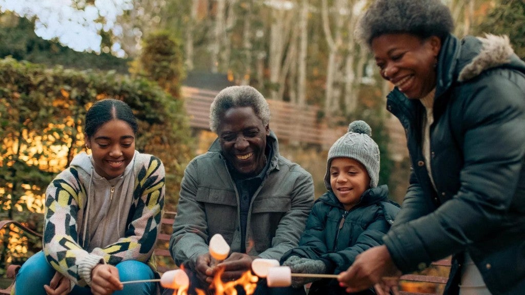 Family roasting marshmallows outside at a fire pit