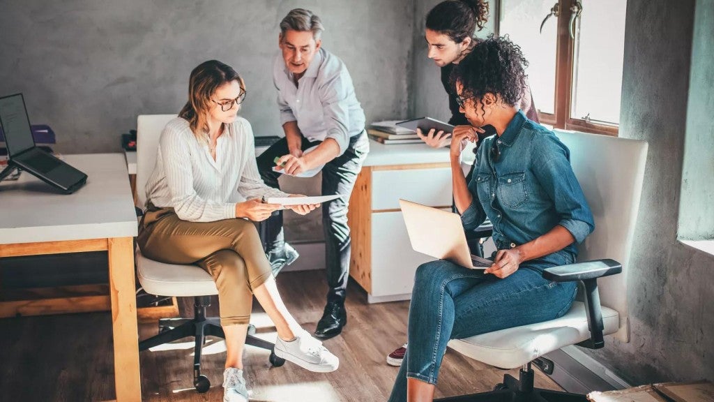 Business owner with three employees gathered together to talk