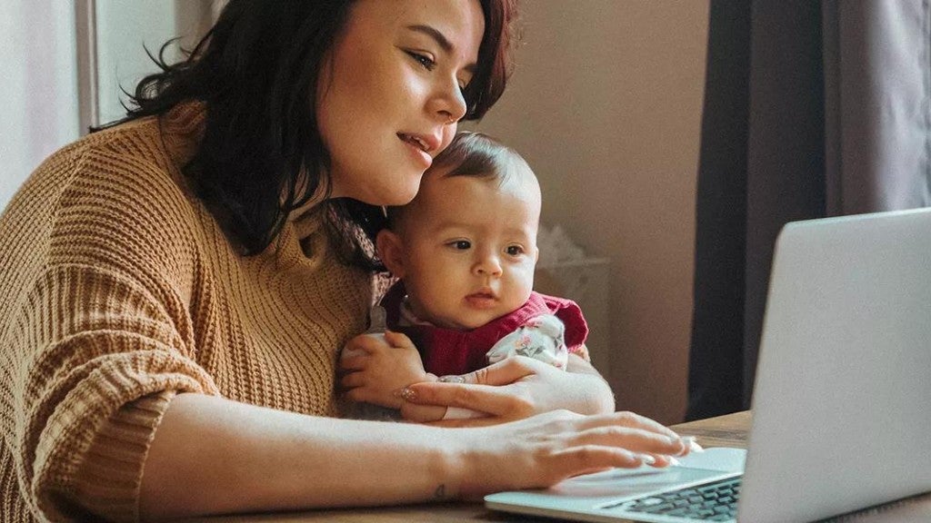 Woman holding a baby on her lap while she looks at her credit score on a computer