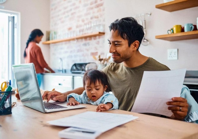 Dad with small child on lap working on financial paperwork