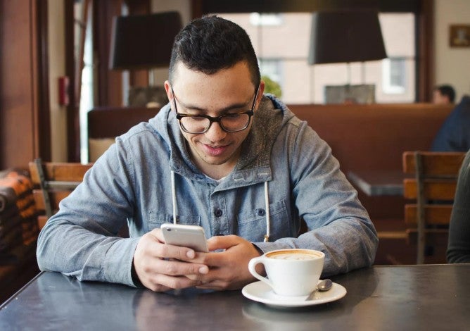 Hombre joven usando su teléfono para informarse sobre cuentas de inversión y términos de productos.