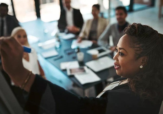 High angle shot of a young businesswoman explaining work related stuff during a presentation to work colleagues in a boardroom.