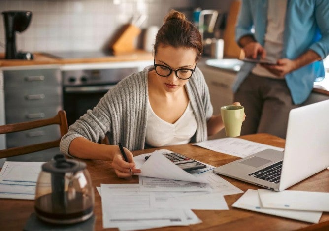 Woman sitting at table with computer working on a budget