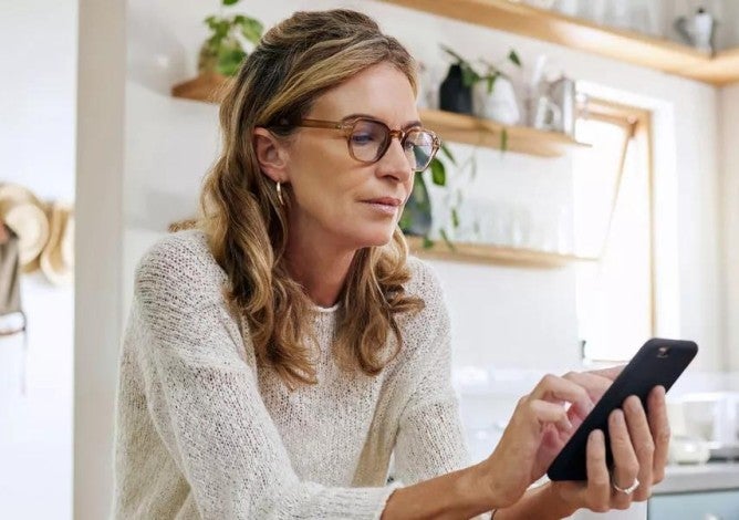  Una mujer mirando similitudes y diferencias entre una cuenta IRA y una cuenta 401(k) en su teléfono.