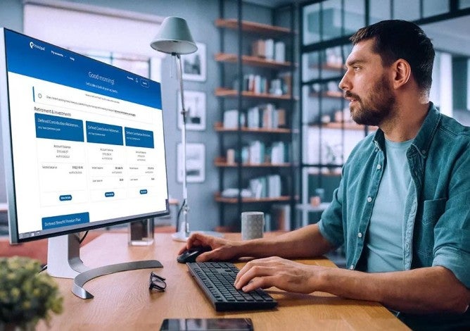 Man sitting at a desk checking his financial information on a desktop computer.