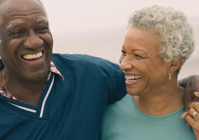 Photo of an older man and woman walking, embracing, and smiling