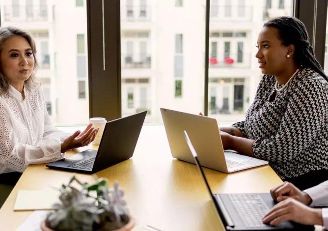 Photo of a diverse group of employees around a conference table having a discussion.