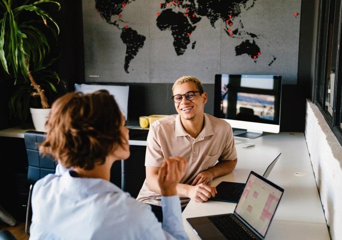 Young employees having a desk-side meeting.