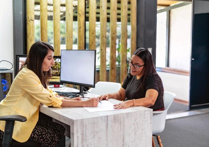 Business decision maker reviewing paperwork with an employee across a desk.