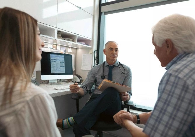 Medical professional sitting with two people discussing health care