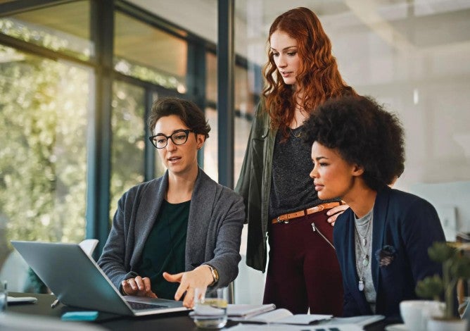 Three women looking at a laptop reviewing the SECURE 2.0 updated rules for 401(k) plans.