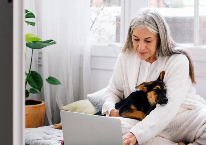 Elderly woman with dog working on laptop