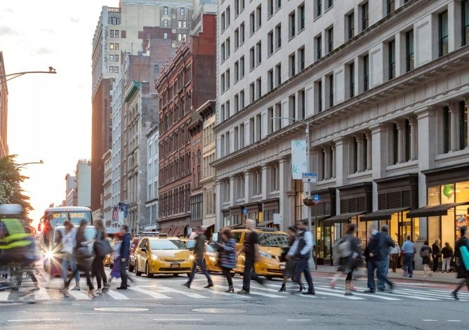 Fast paced street scene with people walking across a busy intersection on Broadway in Manhattan New York City