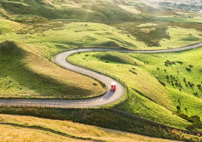 Un coche conduciendo por una carretera sinuosa en un paisaje montañoso