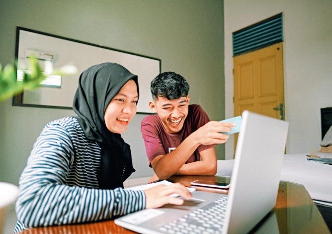 Asian couple looking at their laptop together.