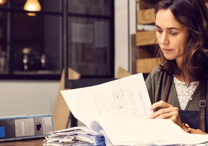 Photo of a woman looking through paperwork. 