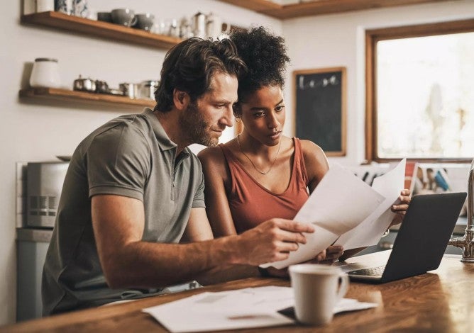 Picture of a couple reviewing paper and digital financial documents.