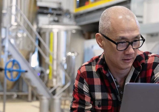 Male brewer using laptop in brewhouse distillery