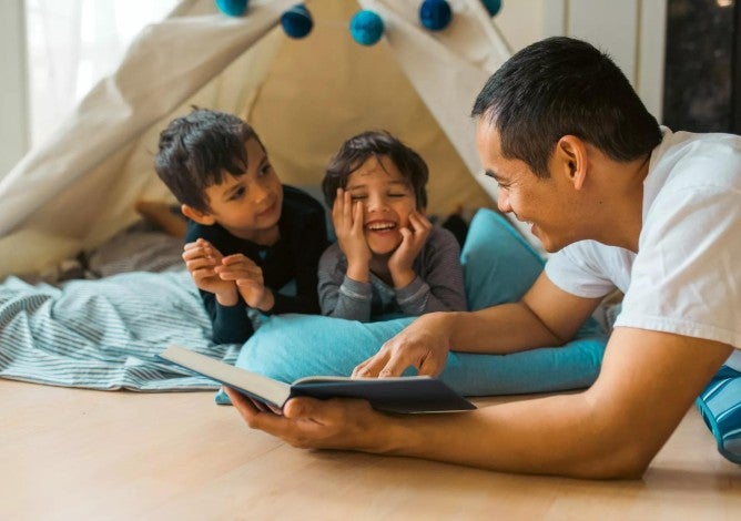 A father reads to his two children and will be sure to look after their needs in his will and estate plan.
