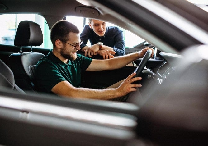 Young man testing new car at a showroom