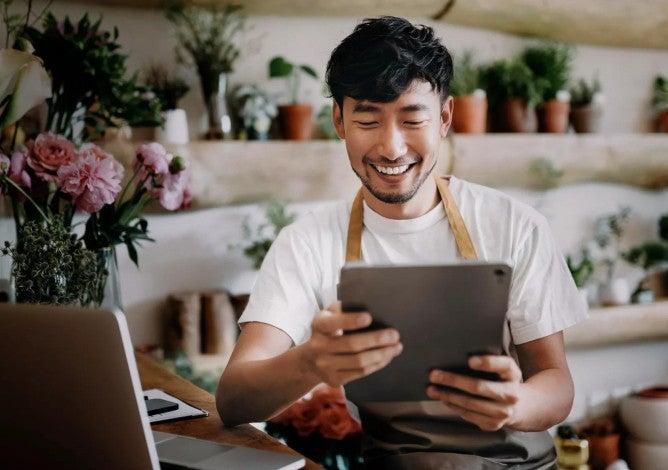 A person in a floral shop reviewing their savings online