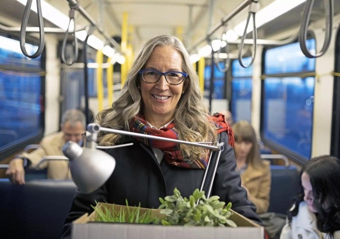 Mature woman who is retiring and on a bus carrying a box of belongings.