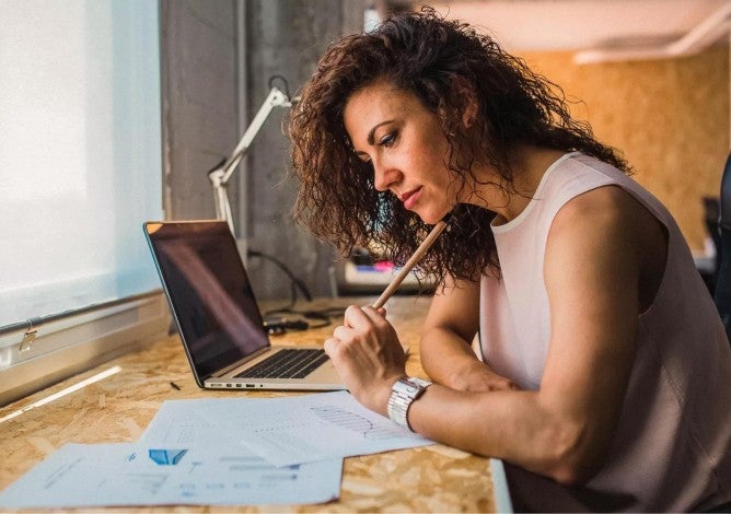 Woman sitting at a desk working on her retirement plan on paper and a computer