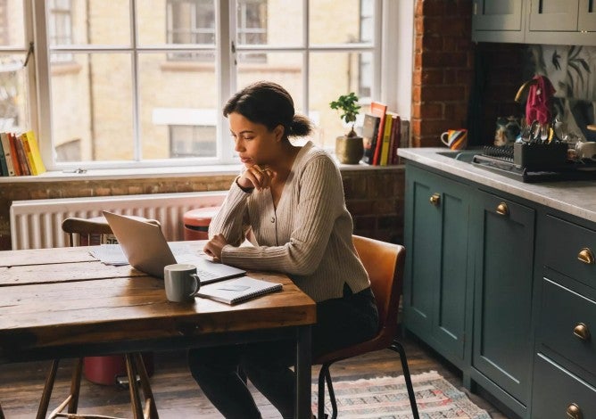 Photo of a woman working on a laptop in her home