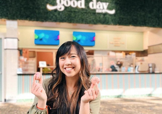 Anna Lam poses with colorful macarons in front of her bakery Good Day DSM.