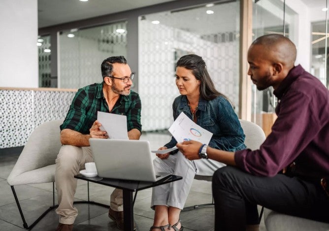 A financial professional sitting with a husband and wife, reviewing retirement documents. 