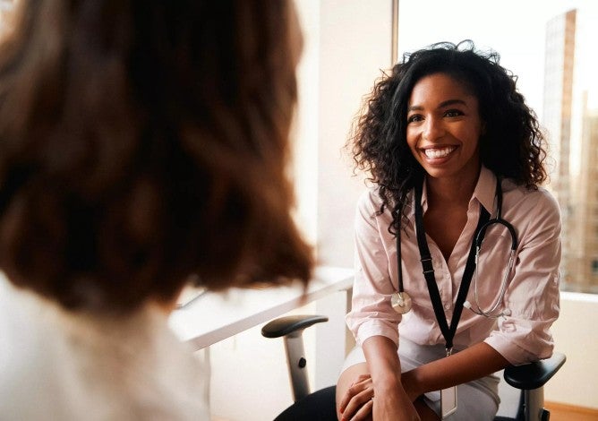 Woman having consultation with female doctor in hospital office.