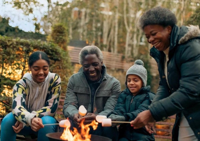 Family roasting marshmallows outside at a fire pit