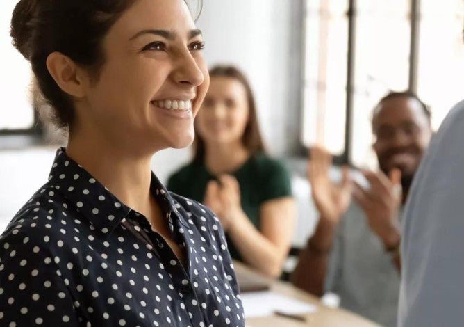 Photo of a woman being applauded by her peers.