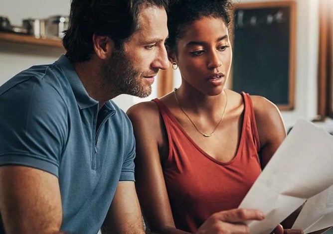 Photo of a couple reviewing paper and digital financial documents.