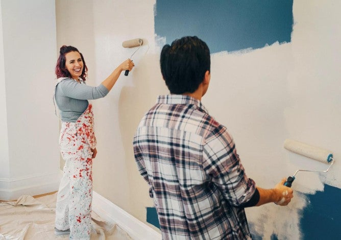 A couple painting a wall in their new home.