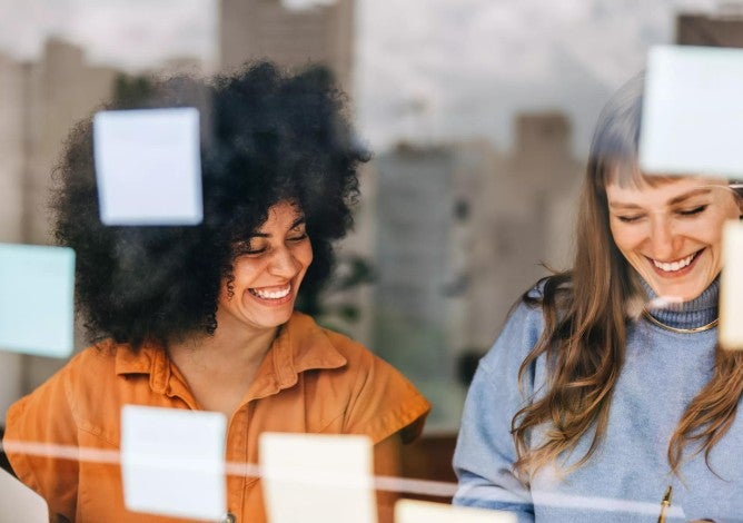 Two woman in an office smiling.