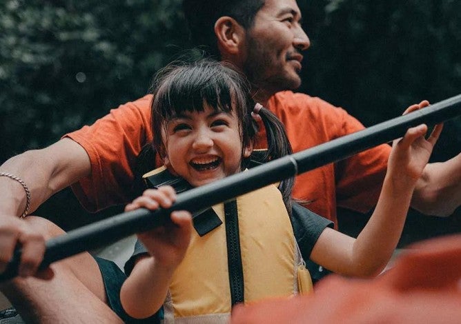 Man and a child rowing together in a canoe