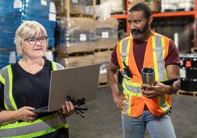 Photo of a small business owner talking to her employees in a warehouse.