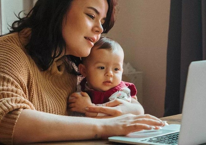 Parent holding child working on laptop