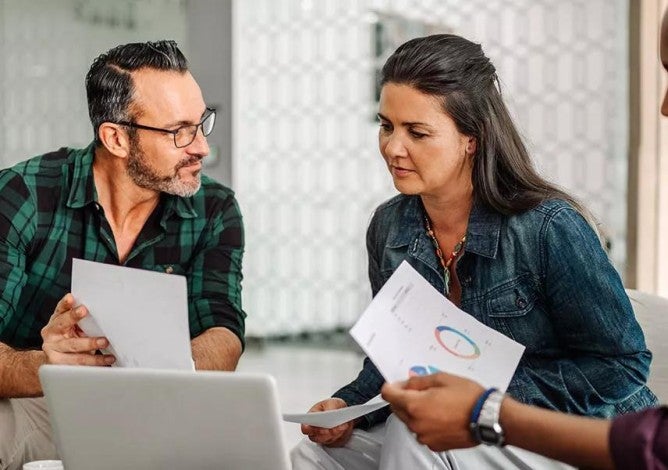 Three people discussing how mutual funds work in front of a laptop.