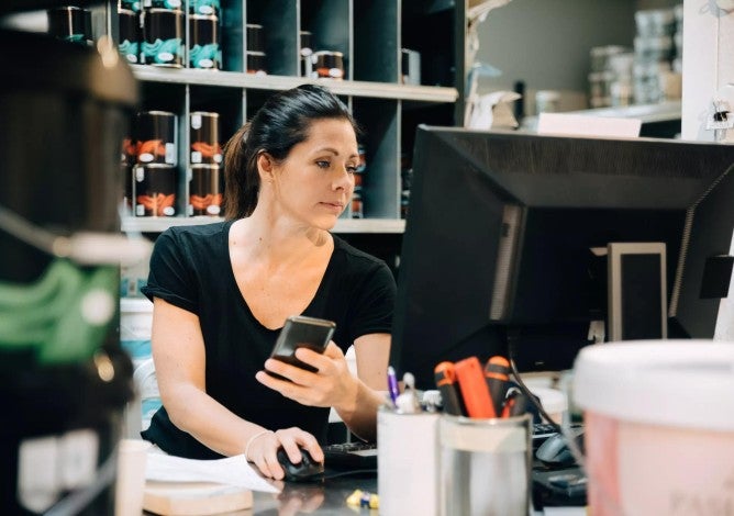 Woman behind a computer in a paint shop looking up information