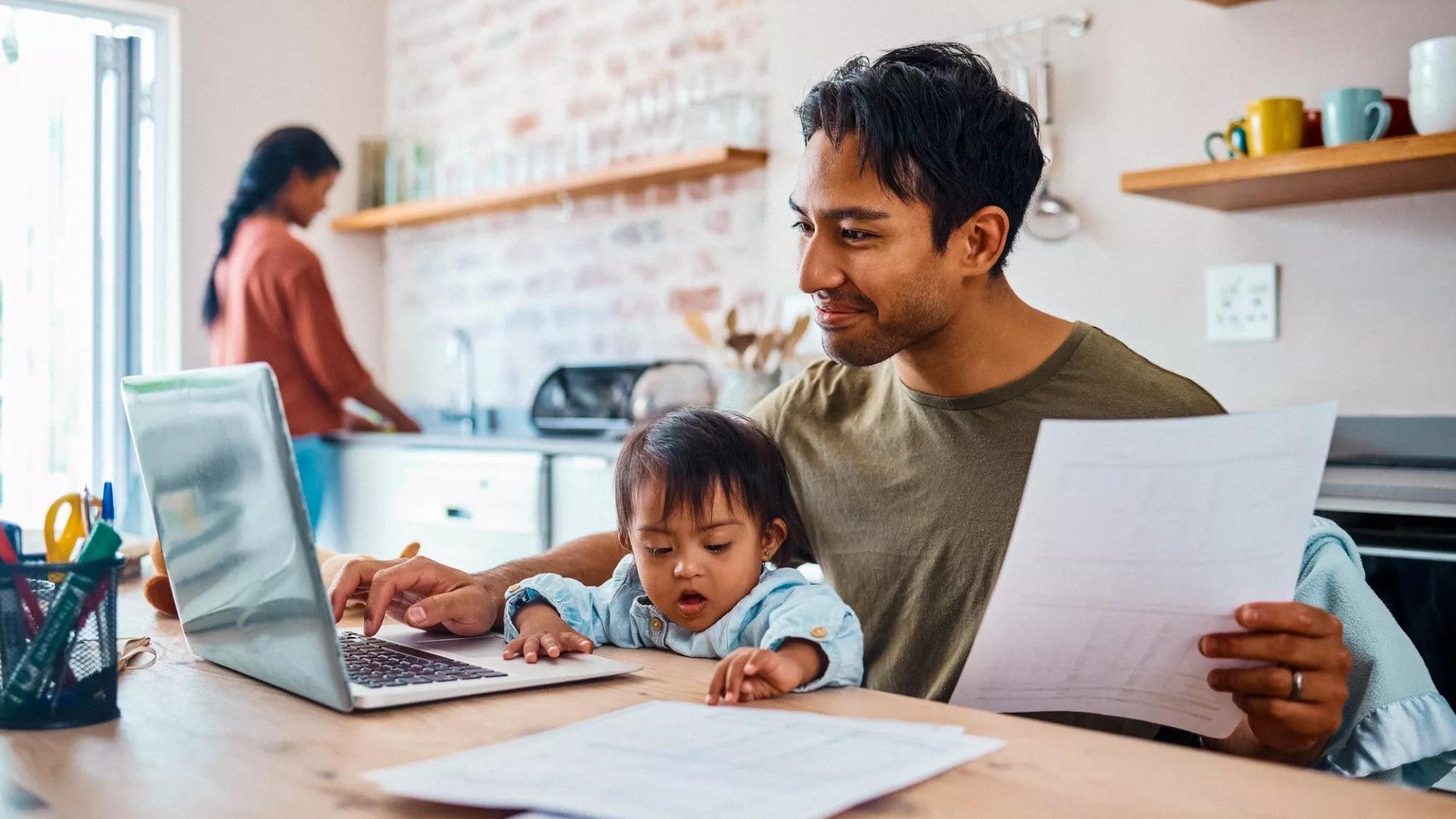 Dad with small child on lap working on financial paperwork 